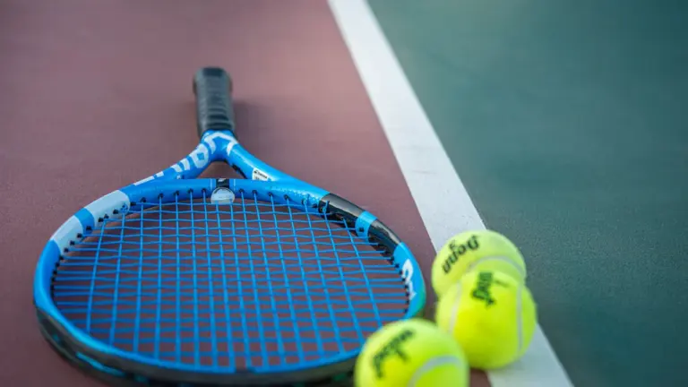 Profesjonalna rakieta tenisowa oraz piłki na nawierzchni kortu przed meczem US Open
