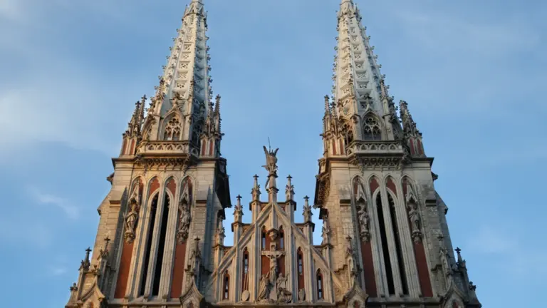 Widok na strzeliste wieże neogotyckiej katedry na tle błękitnego nieba w Kijowie.