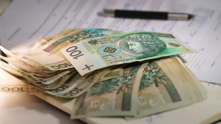 Plik polskich banknotów na dokumentach finansowych przygotowanych do rozliczenia księgowego w firmie.