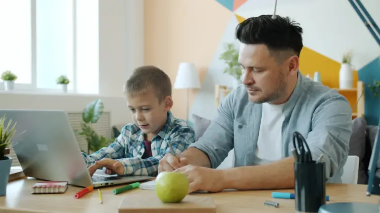 Ojciec pomaga synowi w nauce przy laptopie przed powrotem do szkoły