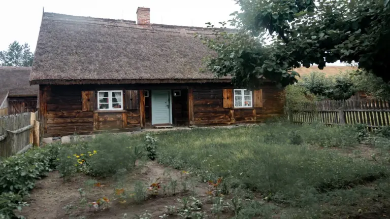Rustykalny drewniany dom z dachem krytym strzechą, typowy dla polskiej wsi i KGW.