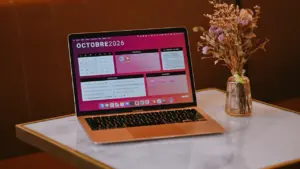 Otwarty laptop na marmurowym stole z kalendarzem na październik 2026 roku.